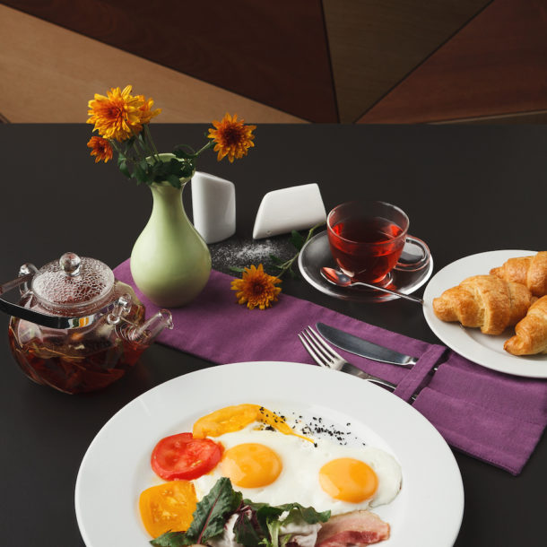 A luxury breakfast of eggs, tea, and croissants